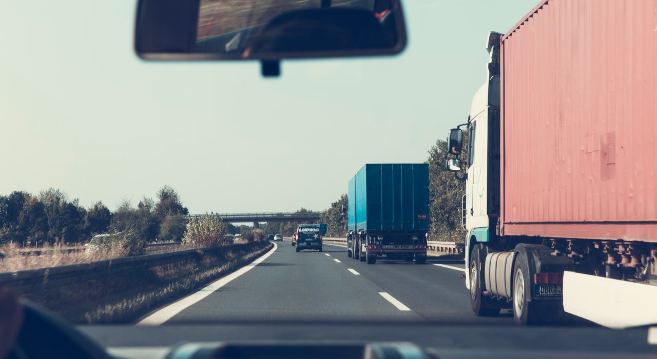 Car driving beside trucks